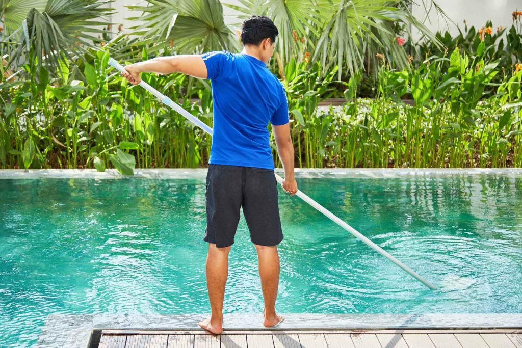 Worker cleaning a residential swimming pool