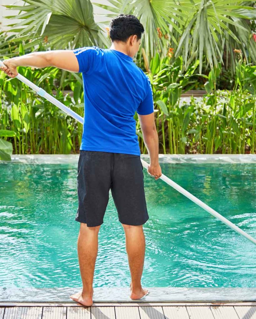 Worker cleaning a residential swimming pool